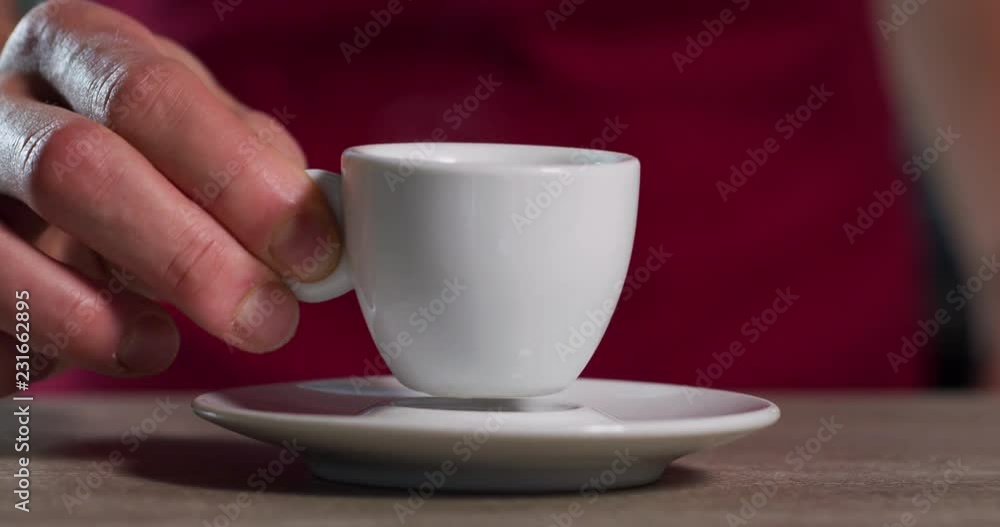 Close up of a barman who just made a coffee while he is putting the coffee cup on the saucer. Close up of a barman who just made a coffee while he is putting the coffee cup on the saucer.