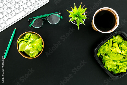 Order healthy food delivery to office. Light, diet meal with lettuce in plastic containers, coffee near computer keayboard and glasses on black background top view copy space photo