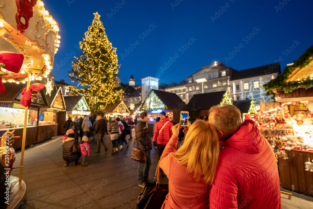 Tourists enjoying Graz Christmas market and taking pictures at the Christmas tree