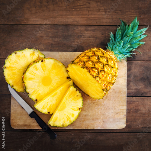 Pineapple on wood texture background. Whole and sliced tropical pineapple on wooden cutting board with copy space. Flat lay