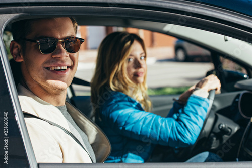 young woman driving car with boyfriend in sunglasses near by, traveling concept © LIGHTFIELD STUDIOS
