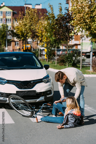 Konstfotografi car driver helping injured young woman to get up after car accident on road