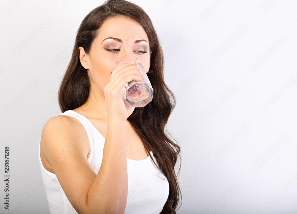 Positive happy smiling woman with healthy skin and long curly hair drinking pure water and looking Positive happy smiling woman with healthy skin and long curly hair drinking pure water and looking