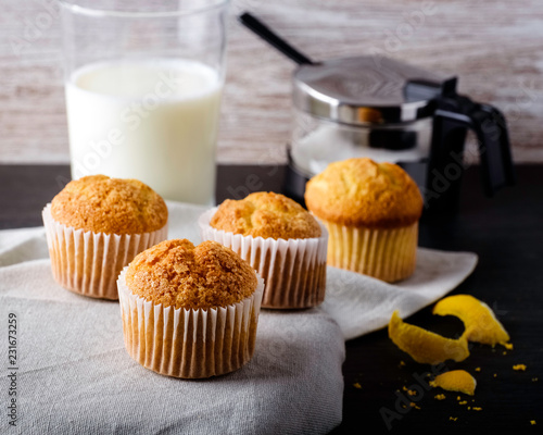 Fresh homemade muffins with lemon, milk and sugar on rustic background.