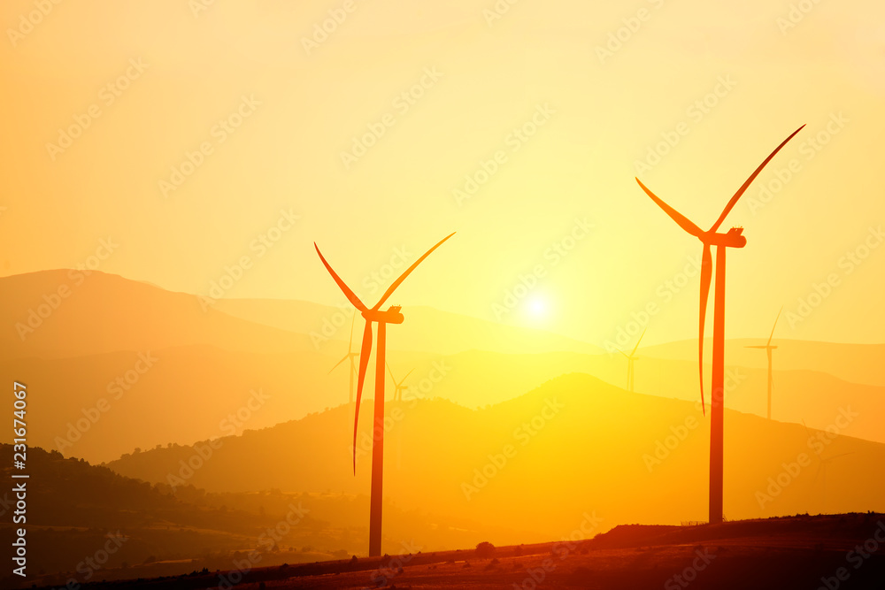 Obraz premium Wind power generators on the background of silhouettes of mountain peaks. Simplicity and minimal lines. Beautiful landscape of the power of nature. 