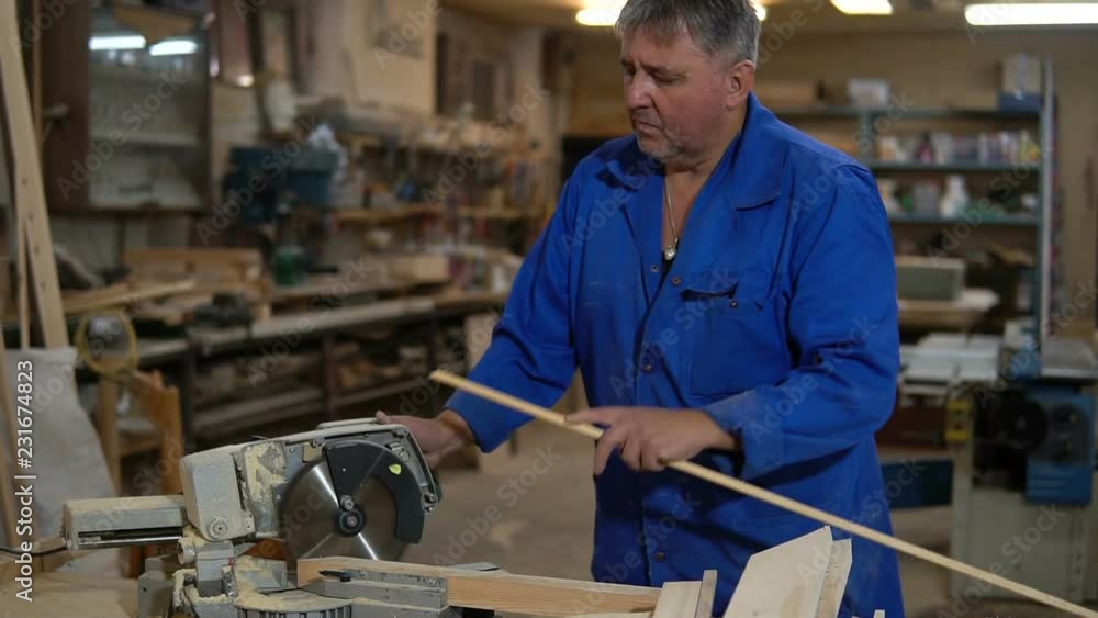 electric saw for sawing boards, worker saws a wooden board in the workshop electric saw for sawing boards, worker saws a wooden board in the workshop