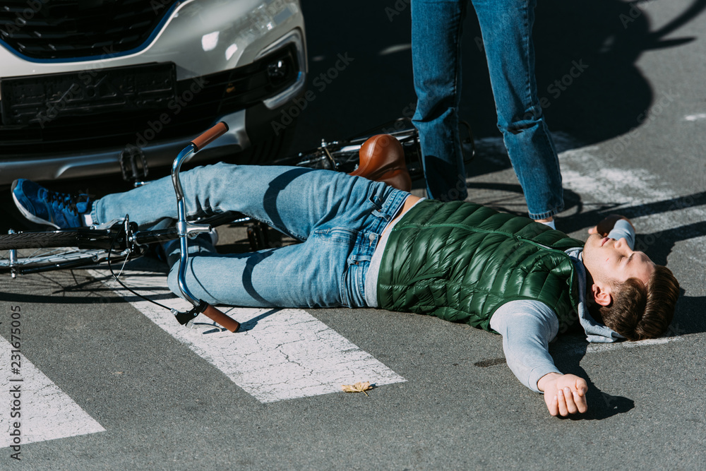 Obraz premium cropped shot of woman standing near injured cyclist after car accident