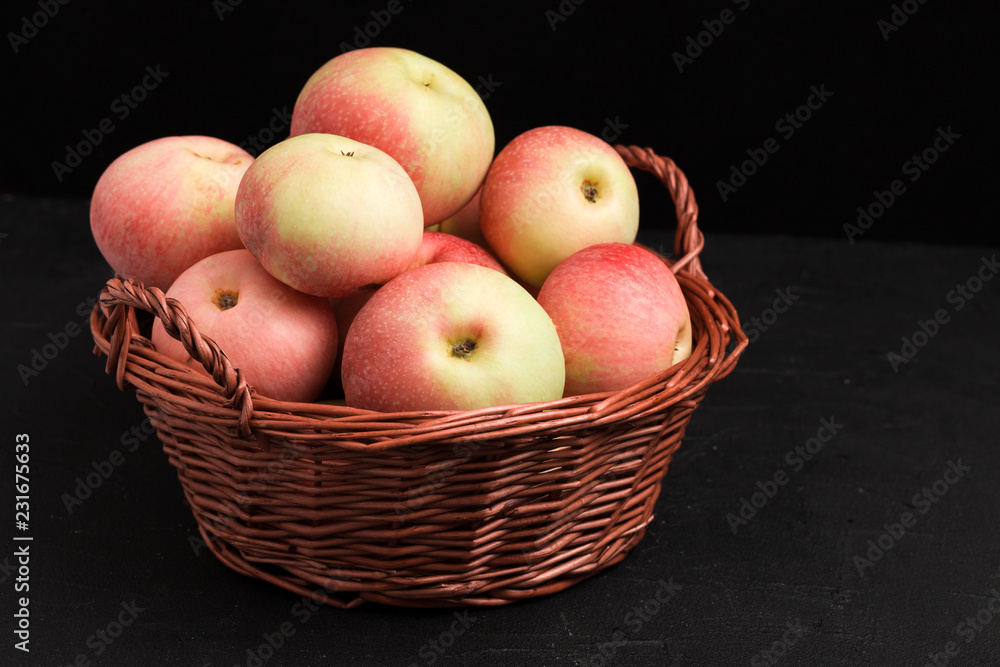 Ripe raw apples in wicker basket on black background with copy space - organic yellow and red fruits. Ripe raw apples in wicker basket on black background with copy space - organic yellow and red fruits.
