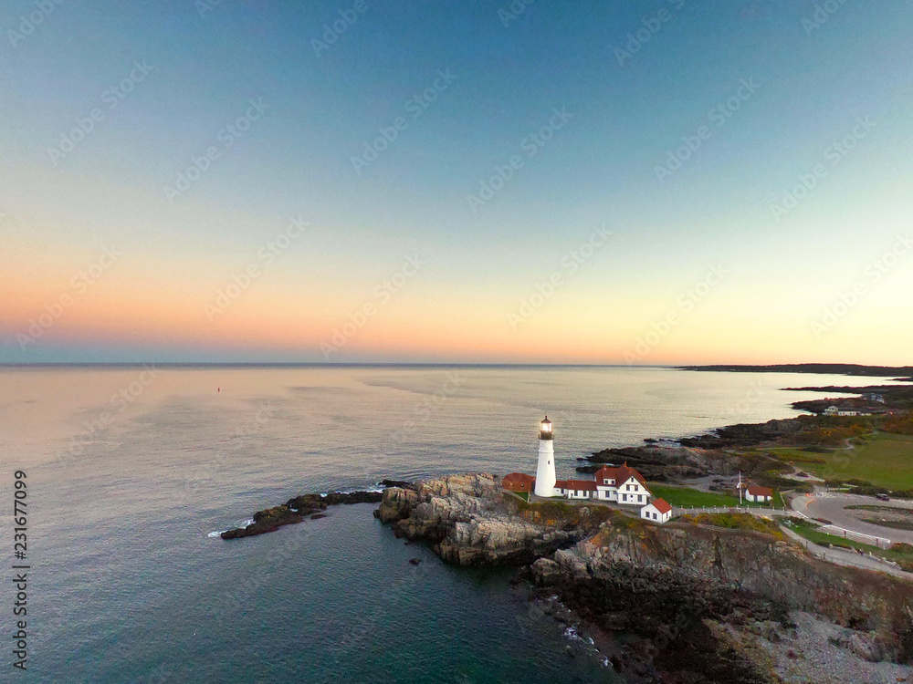 Aerial View of Lighthouse at Sunset Along Rocky New England Coast