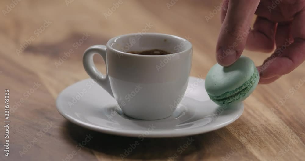 Slow motion man hand put light blue macaron on saucer with coffee cup Slow motion man hand put light blue macaron on saucer with coffee cup