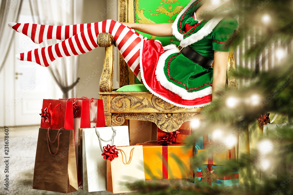 Slim young woman legs in christmas tights. Christmas tree and gifts. Home interior with big window. 