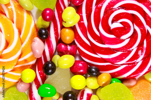 Background of colorful chocolate candies, lollipops, candy cane and jelly sweets