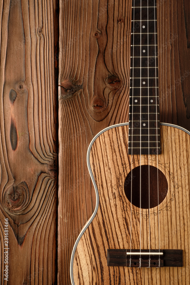 Fototapeta premium tenor ukulele made of zebrawood on aged wood background