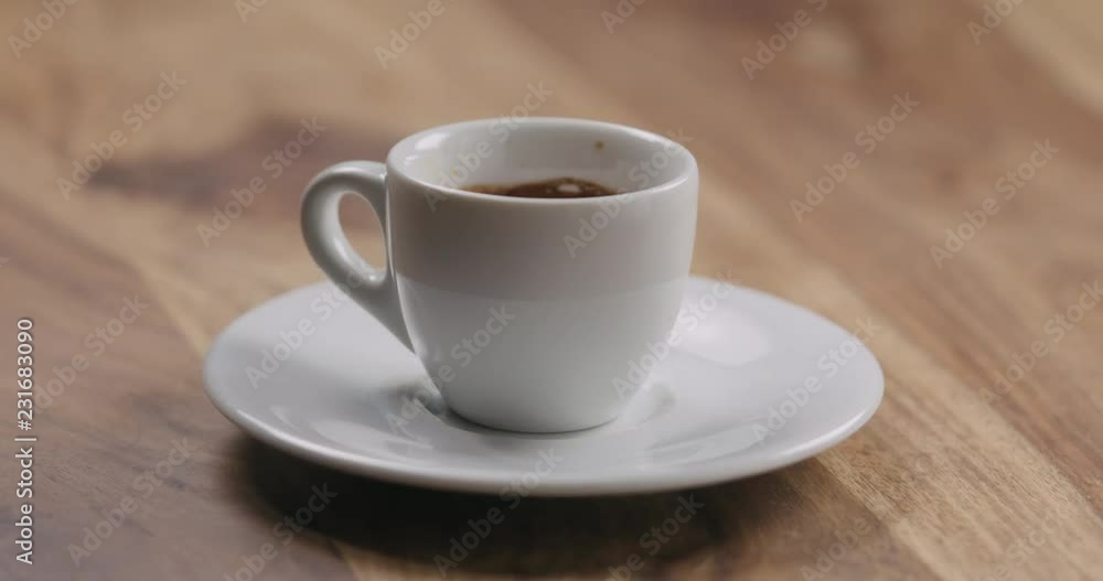 Slow motion man hand put beige macaron on saucer with coffee cup Slow motion man hand put beige macaron on saucer with coffee cup