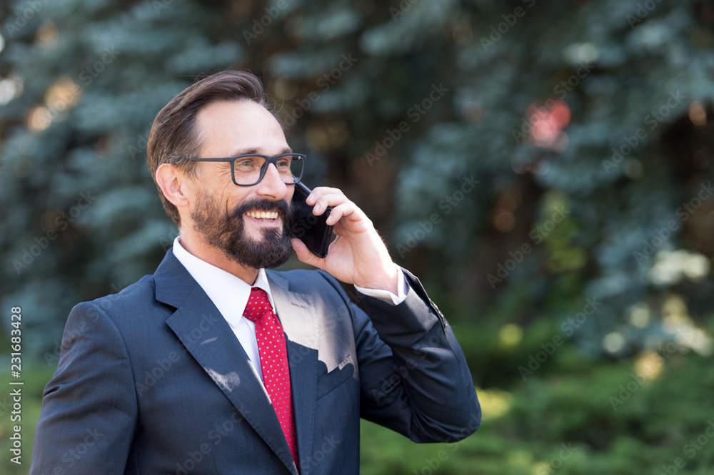 Cheerful lawyer smiling while talking on the phone with his client Cheerful lawyer smiling while talking on the phone with his client