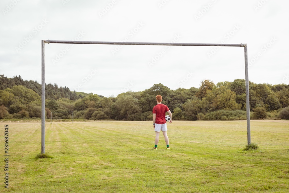 Football player standing with soccer ball in the field Football player standing with soccer ball in the field