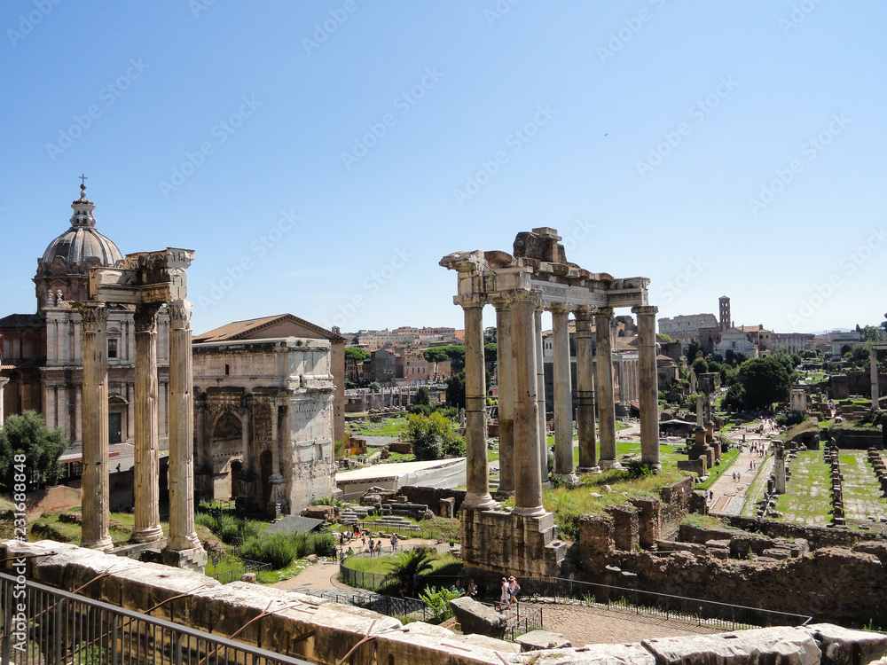 View of the ancient roman forum, with the Colosseum far behind. These two on the foreground are the temples of Saturn and Vespasian.