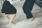 Two young woman dancing barefoot on the white floor