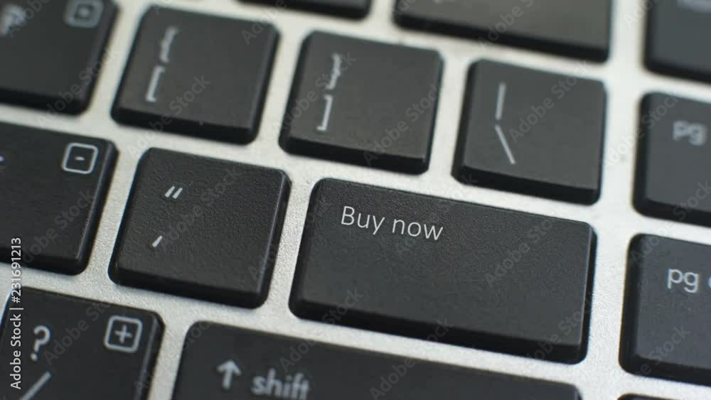 Buy now button on computer keyboard, female hand fingers press key Buy now button on computer keyboard, female hand fingers press key