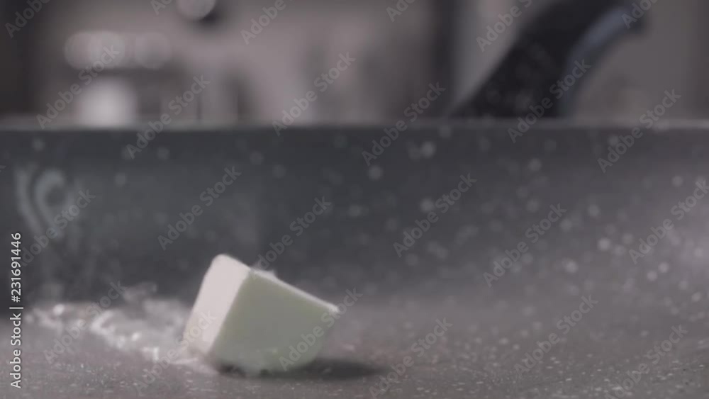 Sliding of the one piece of butter cube on frying pan and melting, slow motion Sliding of the one piece of butter cube on frying pan and melting, slow motion