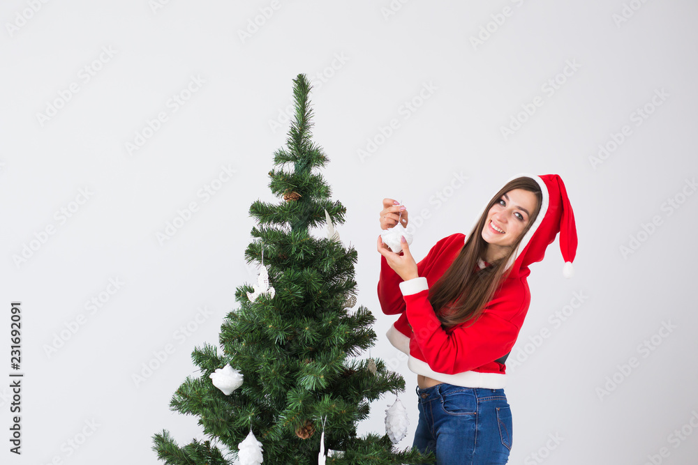 Winter holidays and people concept - Loving couple hanging decorations on Christmas tree on white room background with copy space Winter holidays and people concept - Loving couple hanging decorations on Christmas tree on white room background with copy space