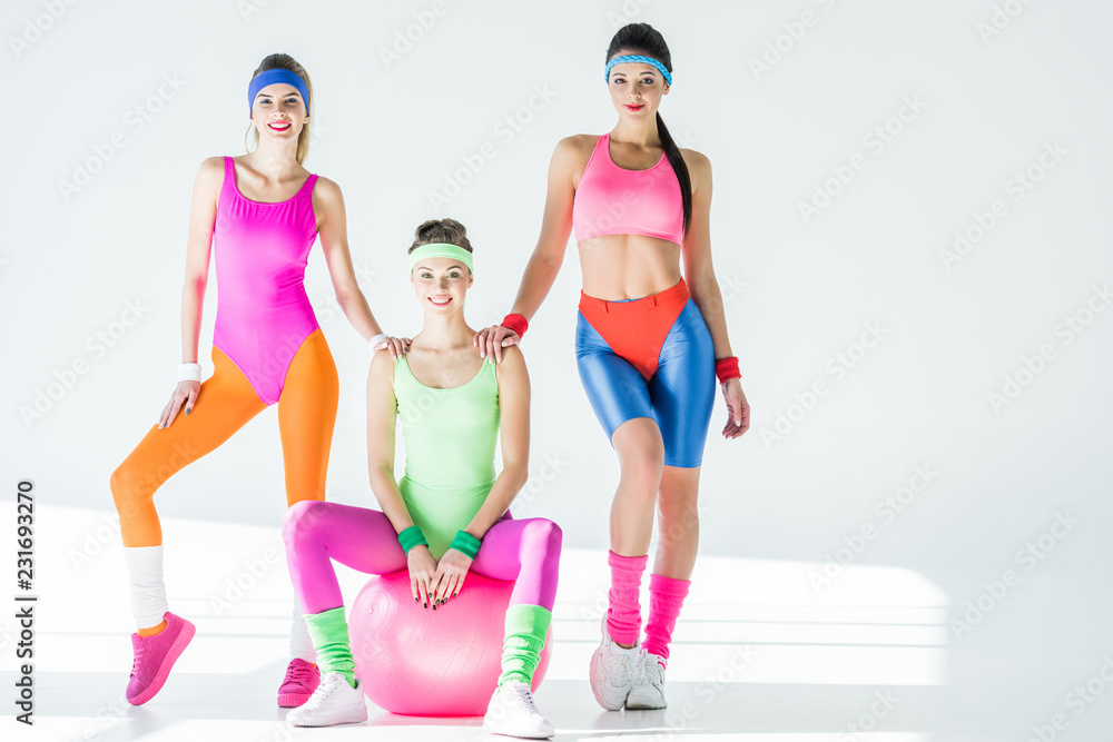 athletic young women in 80s style sportswear smiling at camera on grey  Stock 写真 | Adobe Stock