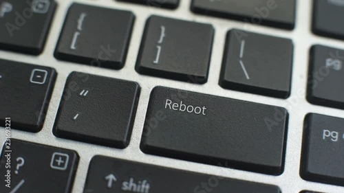 Reboot button on computer keyboard, female hand fingers press key photo