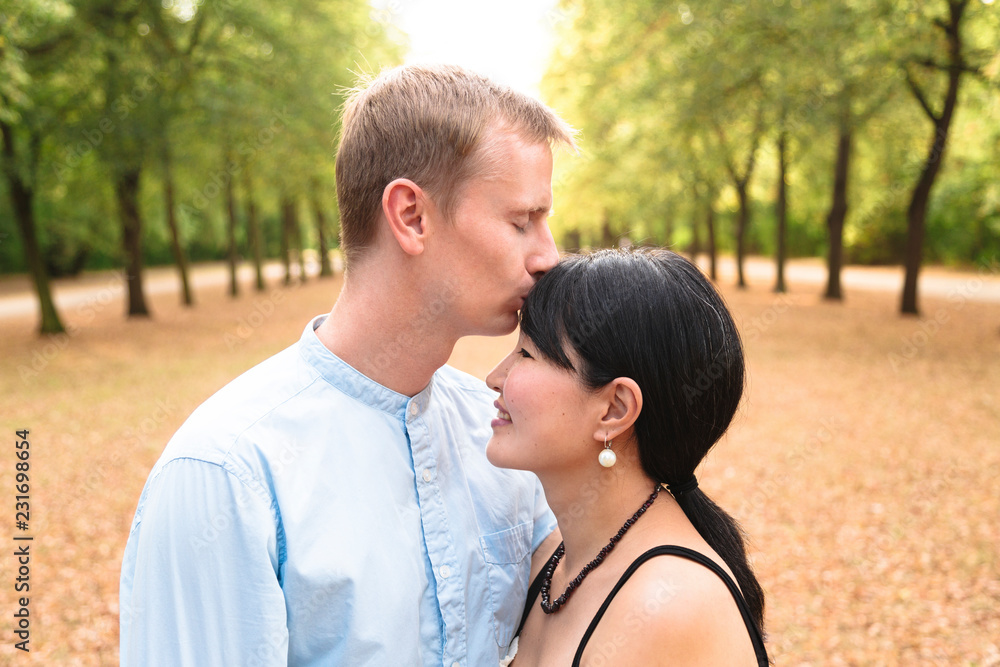 Attractive international couple in beautiful park kissing each other