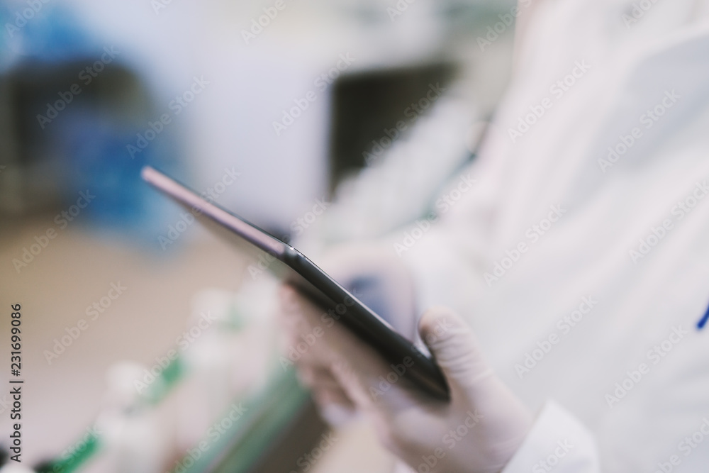Fototapeta premium Close up of tablet in males hands. Man in sterile clothes using tablet .