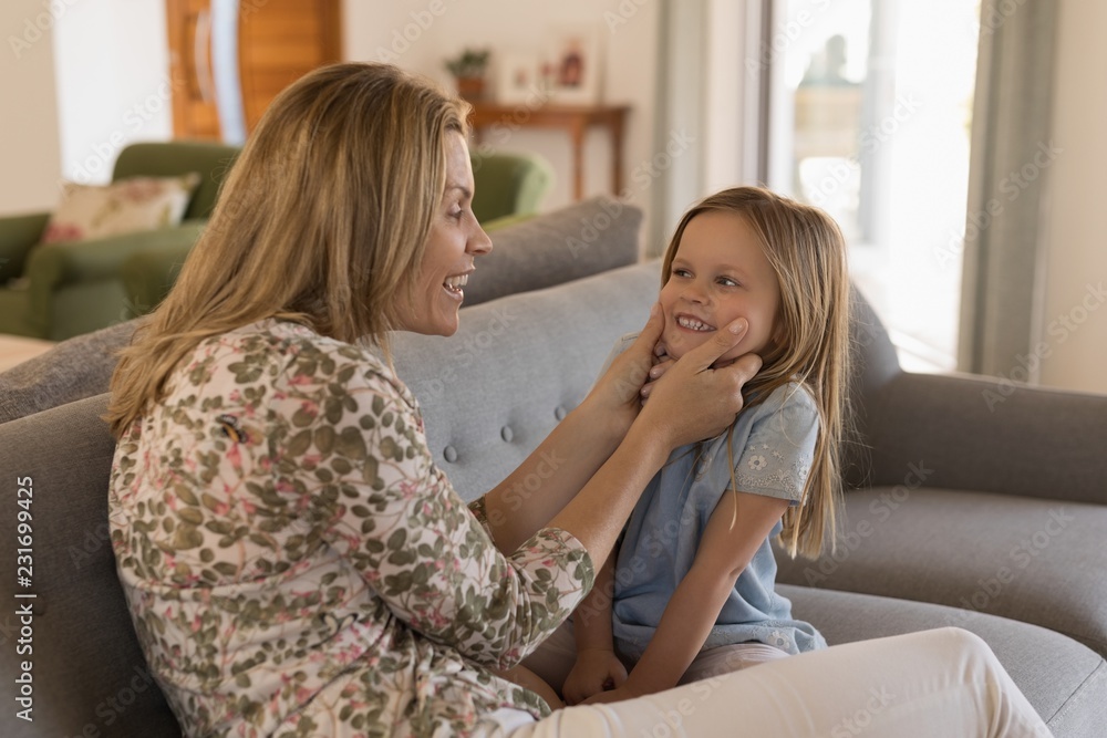 Smiling mother playing with her daughter on sofa at home Smiling mother playing with her daughter on sofa at home
