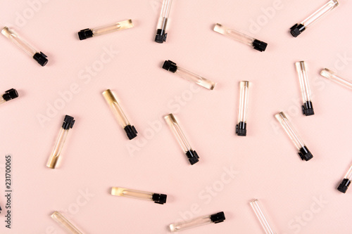 Perfume samples and white flowers on pink background. Top view. Copy space