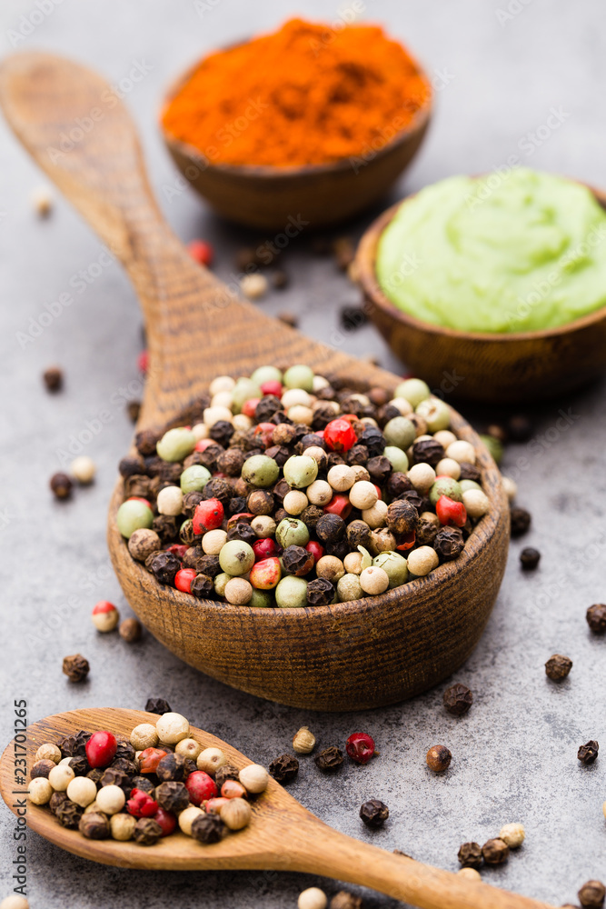 Peppercorn mix in a wooden bowl on grey table. Peppercorn mix in a wooden bowl on grey table.