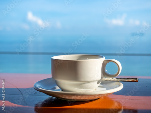 Coffee cup with white dish with seascape view