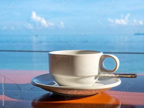 Coffee cup with white dish with seascape view