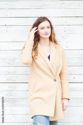 Beautiful ginger woman standing in front of a wooden wall