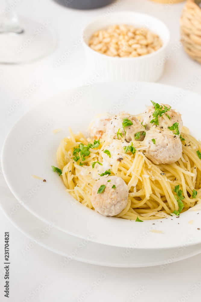 Spaghetti with creamy chicken meatballs served on white plate with pine nuts Spaghetti with creamy chicken meatballs served on white plate with pine nuts