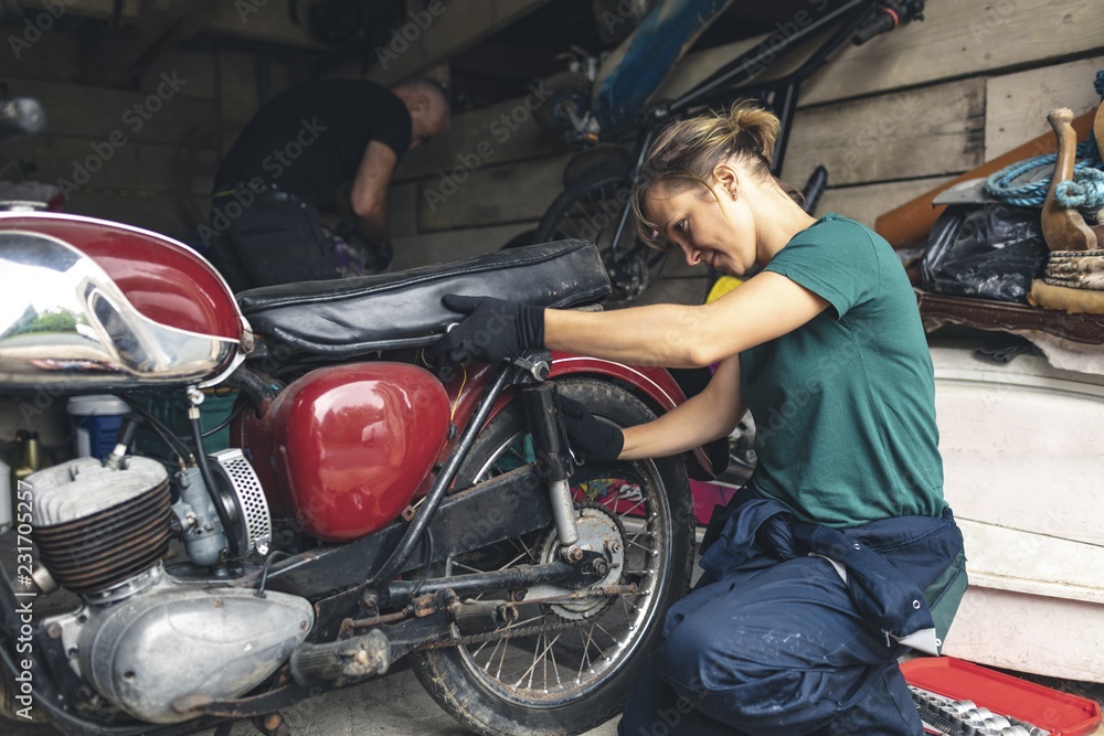 Mechanics repairing motorcycle in workshop Mechanics repairing motorcycle in workshop