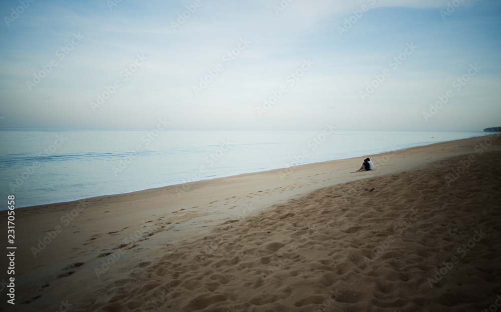 Obraz premium Romantic portrait of attractive couple in love hugs sitting on the beach