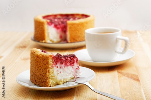 Homemade cheesecake with raspberry on wooden table.