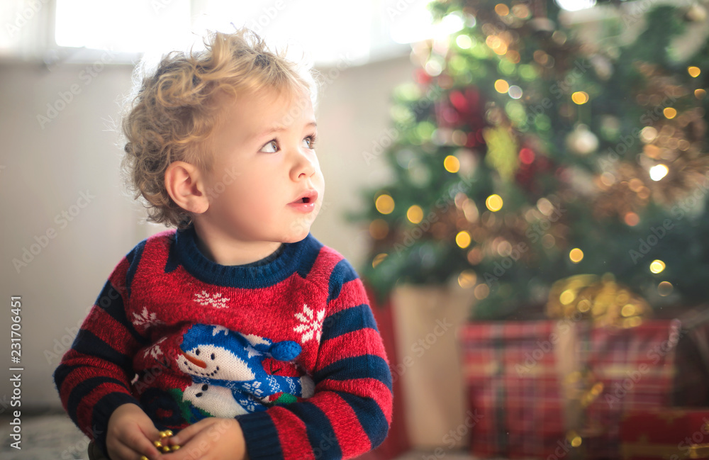 Beautiful child sitting on the carpet, surrounded by christmas gifts Beautiful child sitting on the carpet, surrounded by christmas gifts
