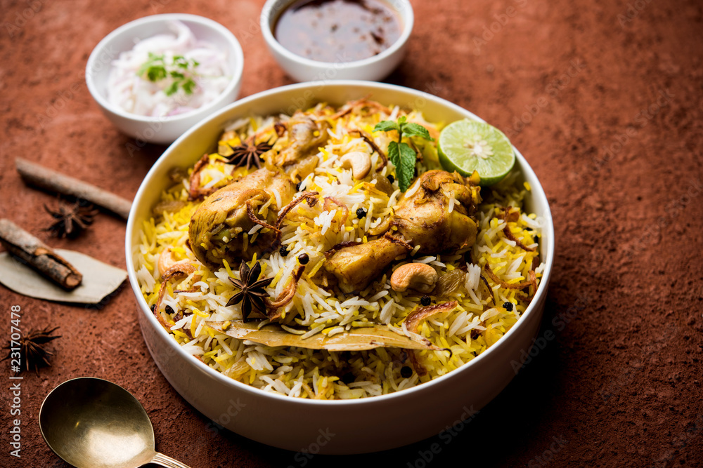 Delicious spicy chicken biryani in bowl over moody background, it’s a popular Indian and Pakistani food.