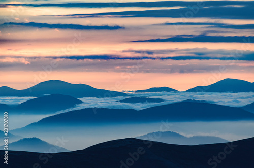 Amazing sunrise high in the mountains with blue and pink mountain silhouettes