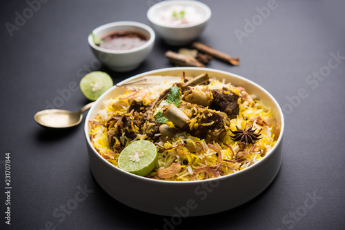 mutton or lamb biriyani with basmati rice, served in a bowl over moody background.