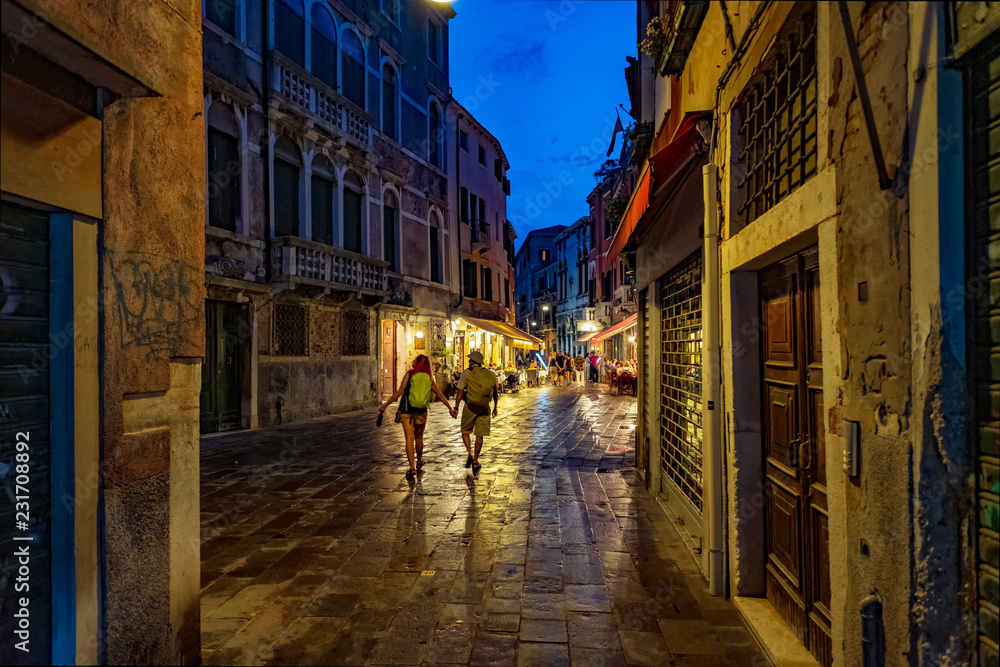 Tourist couple on the night streets of Venice