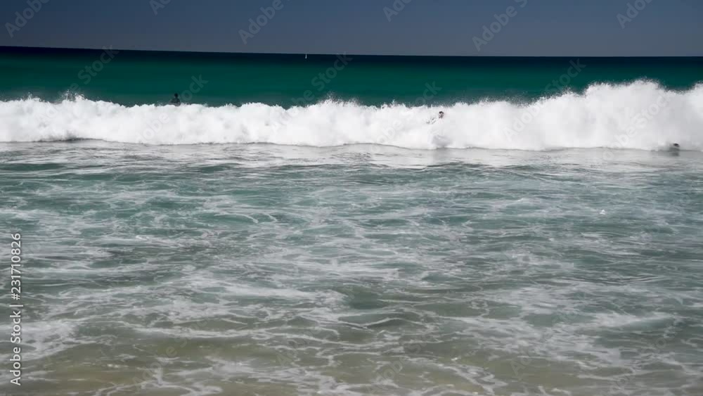 Surfers against waves on a beautiful beach Surfers against waves on a beautiful beach