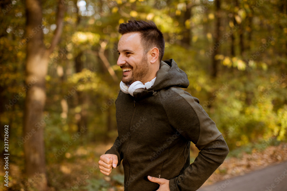 Young man running in the autumn forest with earphones Young man running in the autumn forest with earphones
