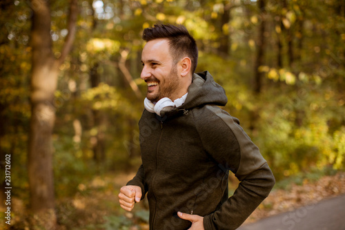 Young man running in the autumn forest with earphones
