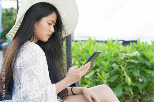 young asian woman holding cellphone near the beach