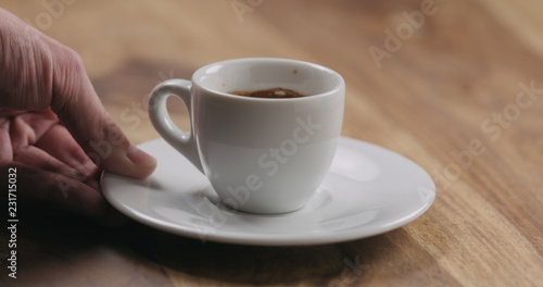 man hand bring cup of fresh espresso on wood table