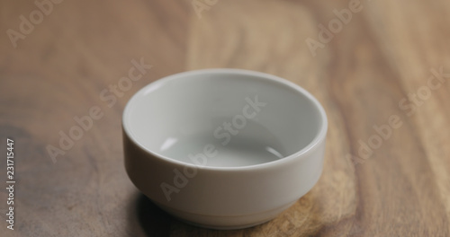 Small empty white bowl on wood background